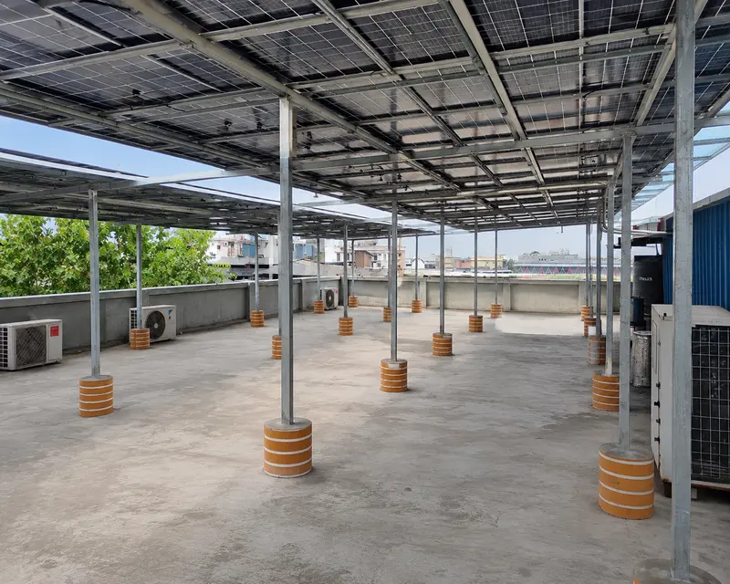 Elevated solar canopy structure over a concrete terrace, columns on painted footings