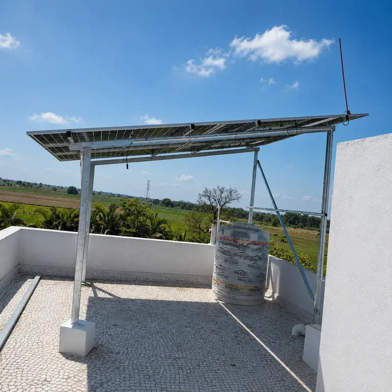 Small tilted solar array on a white farmhouse terrace overlooking green fields